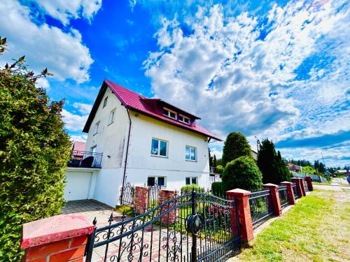 une maison blanche avec un toit rouge et une clôture dans l'établissement VILLA SUNSHINE "SUNSHINE SUITE" NAD JEZIOREM KOMINEK i WANNA w SALONIE OGRóD BALKON, à Lipnica