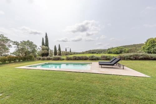 a bench sitting in the grass next to a pool at Mas Xibeques in Báscara