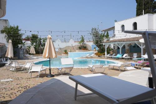 a swimming pool with chairs and umbrellas next to a pool at Hotel Club Perla in Casalabate