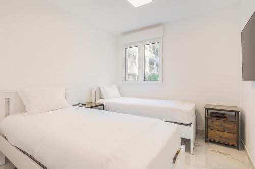 deux lits dans une chambre blanche avec une fenêtre dans l'établissement Port Azur, à Vallauris