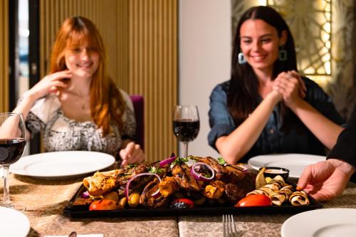 two women sitting at a table with a plate of food at Riviera Spa Resort - Adults Only in Mellieħa