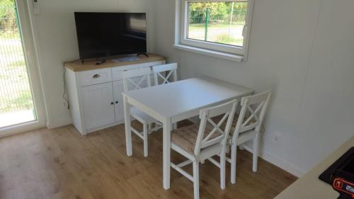 a white table and chairs in a room with a tv at Gyulai Camping en Resort in Gyula