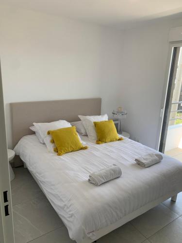- un lit blanc avec 2 oreillers jaunes dans l'établissement Villeneuve Loubet magnifique appartement 2 chambres 6min de la plage, à Villeneuve-Loubet