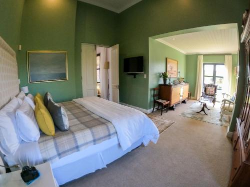 a bedroom with a large bed and green walls at Vineyard Views Country House in Riebeek-Kasteel