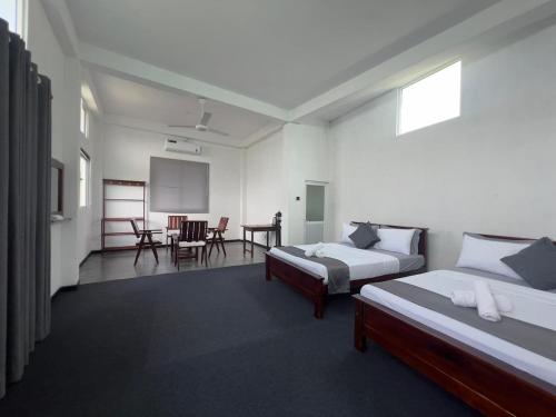 a bedroom with two beds and a table and chairs at Kandy Alpine Breeze in Kandy