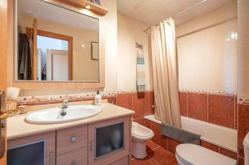 a bathroom with a sink and a toilet and a mirror at Apartamento Bahía Golf Suites in El Puerto de Santa María