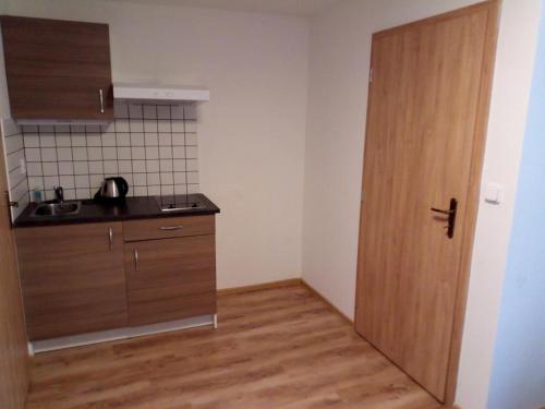 a kitchen with a wooden door in a room at Apartmány pod Lípami - Harrachov in Harrachov
