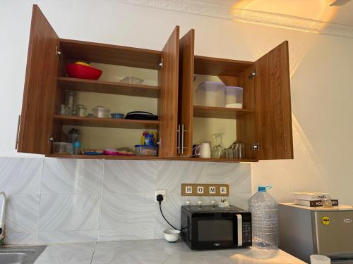 a kitchen with wooden cabinets and a microwave on a counter at Aligna Bamburi in Mombasa