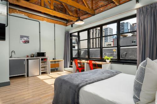 a bedroom with a bed and a kitchen with windows at 53 on Castle by Neighbourgood in Cape Town