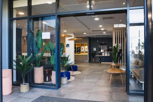 un hall d'entrée avec des plantes en pot dans un immeuble dans l'établissement Kyriad ECO - Clermont Ferrand Estaing, à Clermont-Ferrand