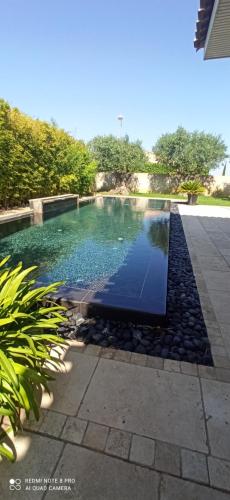- une piscine avec des rochers dans une cour dans l'établissement Le Pérignan maison 3 chambres piscine, à Fleury