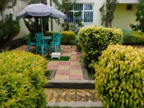 a patio with two chairs and a table with an umbrella at Avi-Pension in Addis Ababa