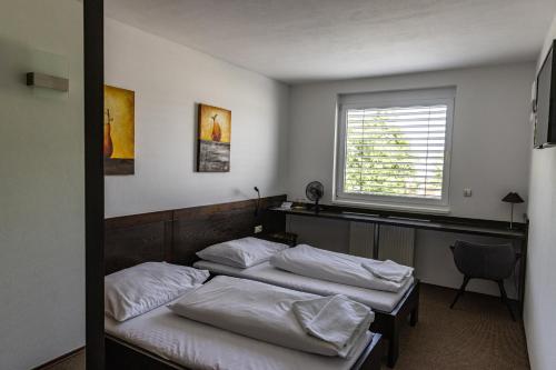 two beds in a room with a window at Penzion Royal in Trenčín