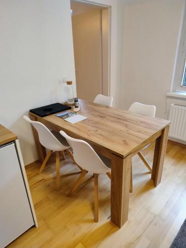 a wooden table with white chairs in a room at CityLeaves Apartments TWO in Sankt Aegyd am Neuwalde