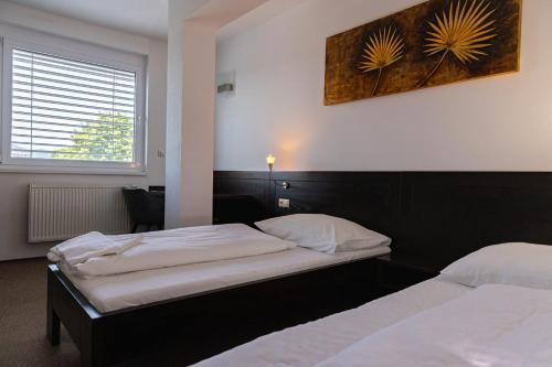 a bedroom with two beds and a picture on the wall at Penzion Royal in Trenčín