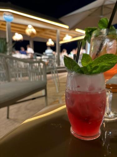 a drink sitting on a table with a mint leaf in it at Paguro Beach Hotel in Siculiana Marina
