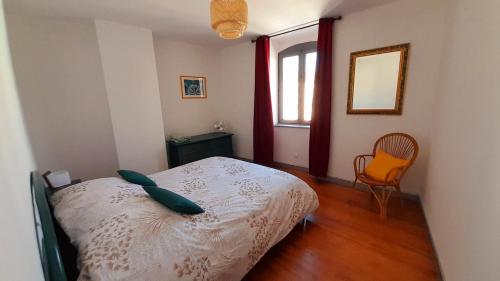 una camera da letto con un letto, una sedia e una finestra di Bergamote a Villeneuve-de-Berg