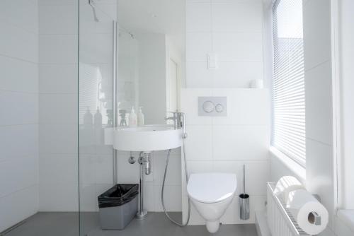 a white bathroom with a toilet and a sink at Omena Hotel Turku Kauppiaskatu in Turku