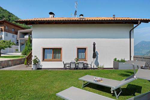 a white house with a table and chairs in the yard at Apartement Huck in Cornedo all'Isarco
