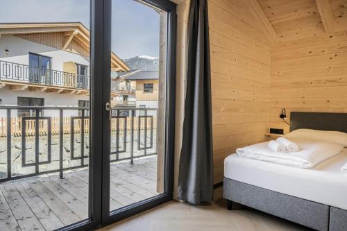a bedroom with a bed and a large window at Clofers Nature Chalets Obermöschach in Hermagor
