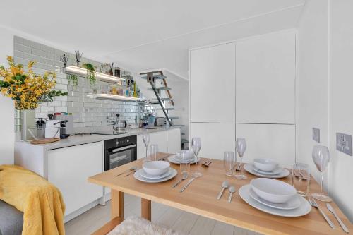 a kitchen with a wooden table with plates and glasses at On the Water 7 Free Parking By My Getaways in Brighton & Hove
