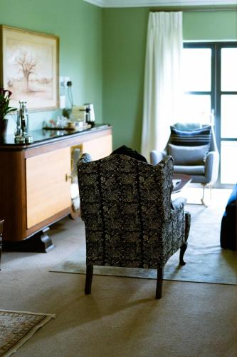 a living room with a chair and a table at Vineyard Views Country House in Riebeek-Kasteel