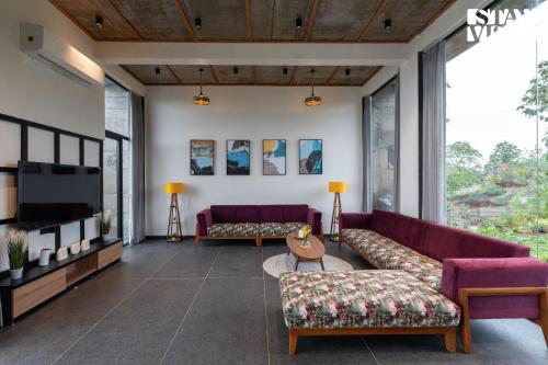 a living room with purple couches and a tv at StayVista at The Solitaire Home with BBQ, Lawn, AC in Dhamni