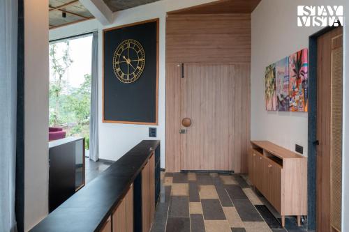 a hallway with a door and a clock on the wall at StayVista at The Solitaire Home with BBQ, Lawn, AC in Dhamni
