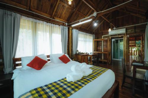 a bedroom with a large white bed with red pillows at บ้านสวนแก้วคำแพง Baan Suan Kaew Khampaeng in Udon Thani