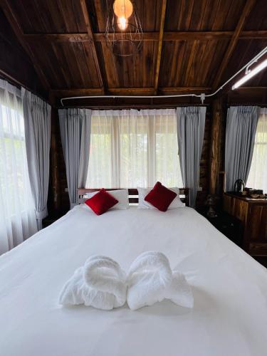 two towels on a white bed in a room with windows at บ้านสวนแก้วคำแพง Baan Suan Kaew Khampaeng in Udon Thani