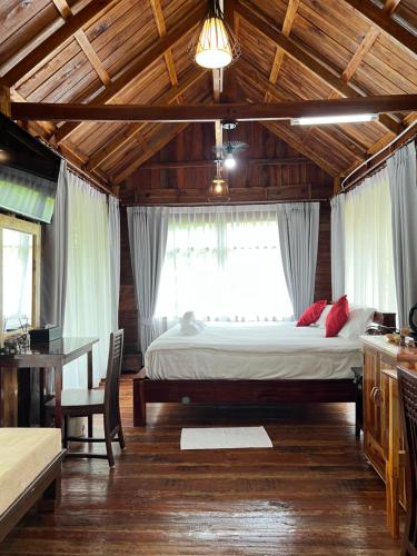 a bedroom with a large bed in a wooden ceiling at บ้านสวนแก้วคำแพง Baan Suan Kaew Khampaeng in Udon Thani