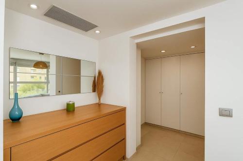 a room with a wooden dresser and a mirror at Magnificent 3BR-2BA in Marina Herzliya w Pool in Herzliyya B