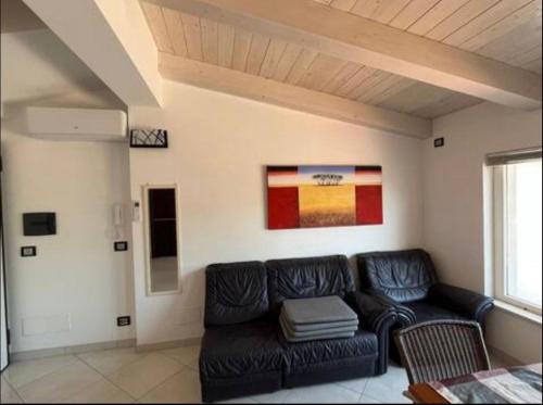 a living room with a black leather couch in a room at b&b montauro in Montepaone Lido