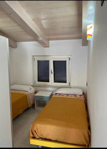two beds in a room with two windows at b&b montauro in Montepaone Lido