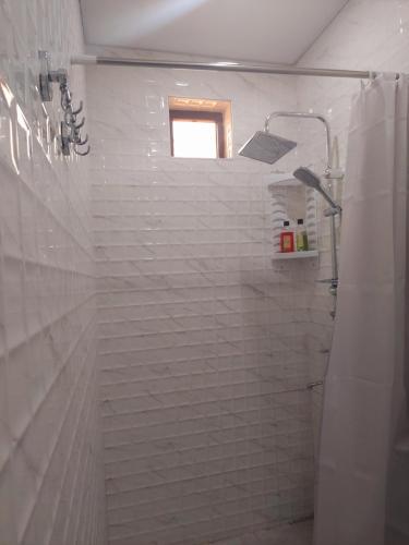 a bathroom with a white tiled shower with a window at Come & Rest in Stepantsminda