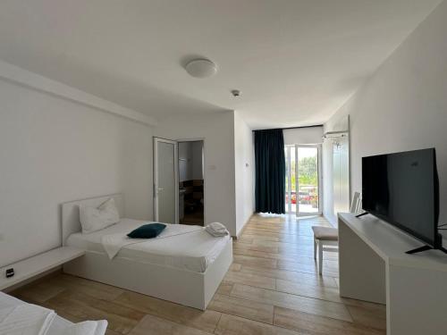 a white room with a bed and a flat screen tv at Pensiunea La Miluta in Caraorman