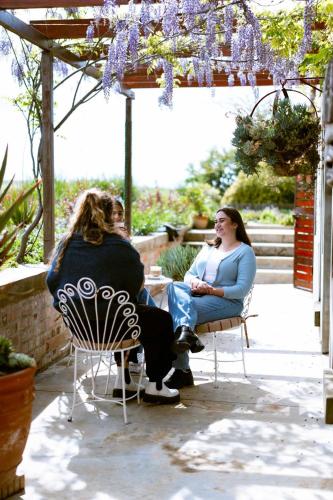 two women sitting in chairs on a patio at Vineyard Views Country House in Riebeek-Kasteel