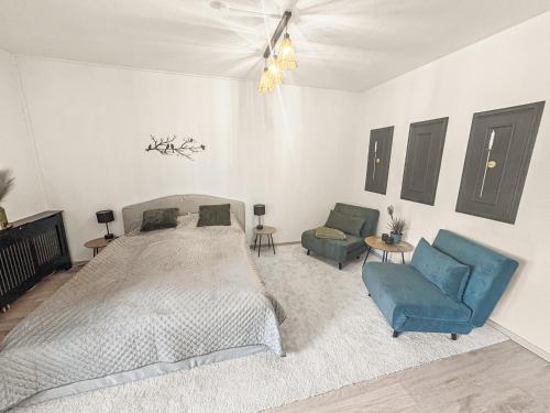 a bedroom with a bed and two blue chairs at Ankerplatz 2 - Hafenblick, Parkplatz, modern in Bad Zwischenahn