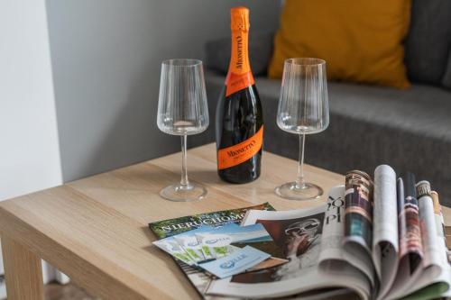 a table with a bottle of wine and two wine glasses at Przystanek Jantar - pokoje i apartamenty in Jantar