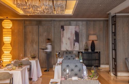 a person standing in a dining room with two tables at Park Hyatt Johannesburg in Johannesburg