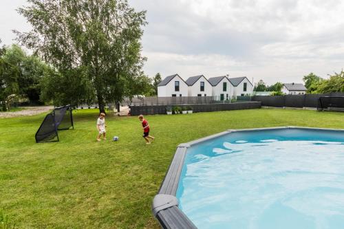two children playing with a soccer ball next to a pool at Przystanek Jantar - pokoje i apartamenty in Jantar