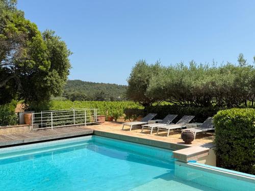 une piscine avec des chaises longues et des arbres dans l'établissement Villa La Londe-les-Maures au milieu des vignes, à La Londe-les-Maures