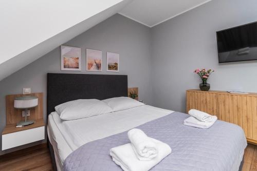 a bedroom with a bed with two white towels at Przystanek Jantar - pokoje i apartamenty in Jantar