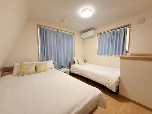 a bedroom with two beds and a window at 池袋銀婚屋 GINKOU's HOUSE -- 2 min train to Ikebukuro Sunshine City in Tokyo