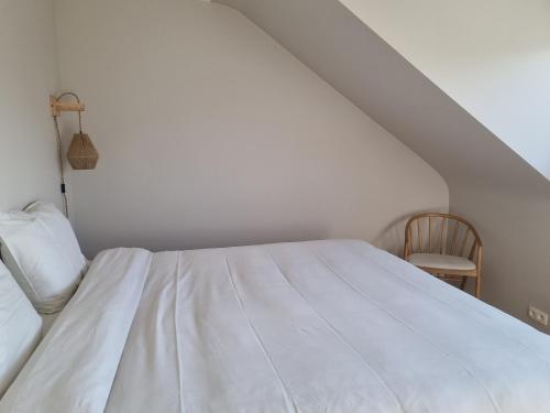 a white bed in a room with a chair at Studio Luna in Tongeren
