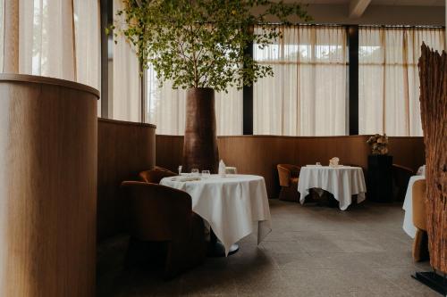 a dining room with two tables and a tree at Hotel Gastronomique de Echoput in Apeldoorn