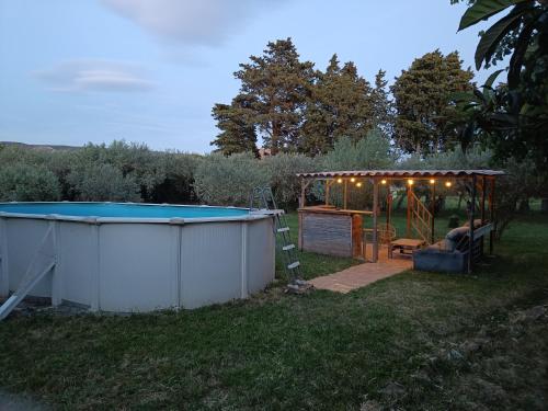 un homme assis sur une chaise sous un kiosque avec une piscine dans l'établissement Véritable maison de campagne nouvellement rénovée au pied du Lubéron, à Cheval-Blanc