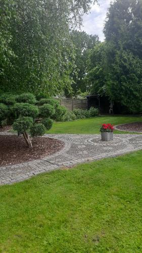 a garden with a stone path and a pot of flowers at Klimatyzowany domek letniskowy Świnoujście in Świnoujście