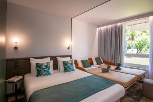 a hotel room with two beds and a window at Novotel Nice Aéroport Cap 3000 in Saint-Laurent-du-Var