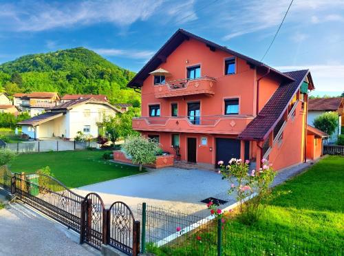 a orange house with a fence in a yard at Apartman Una Paradies in Bihać